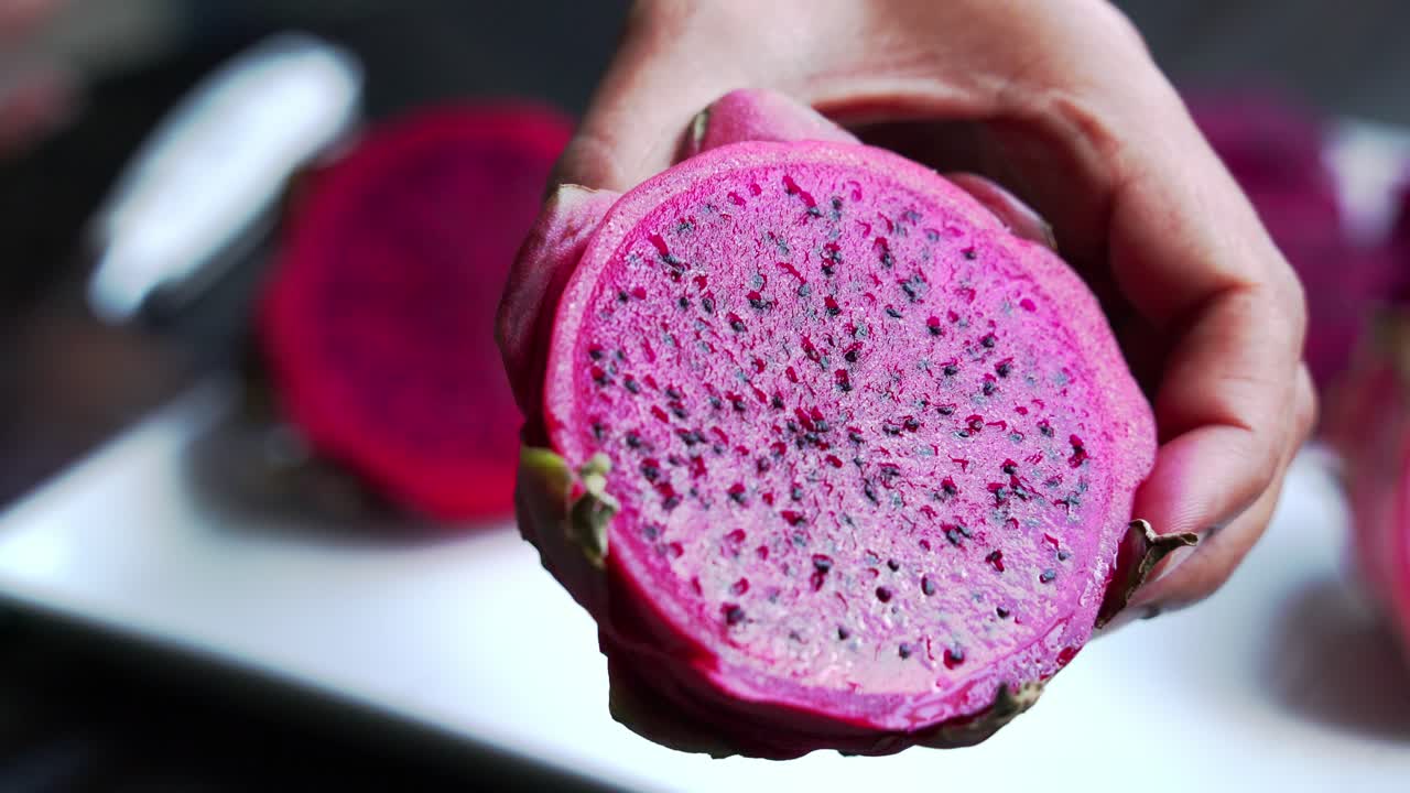 manos sosteniendo frutas de dragón de cerca de frutas de dragon rojas y blancas rebanadas de frutas del dragón rojo y cultivando plantas exóticas pitaya