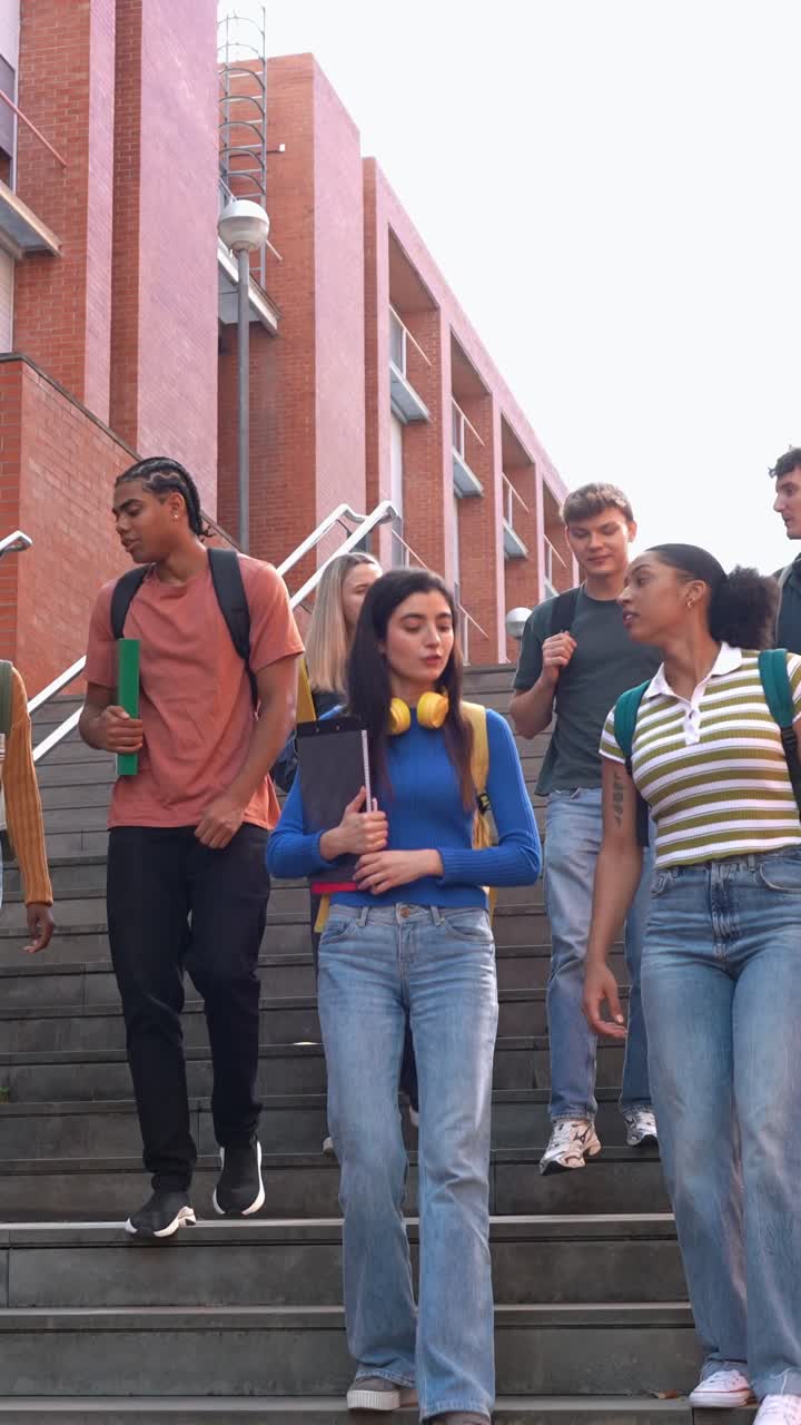 Mangfoldig gruppe glade studenter går ned trappen på campus
