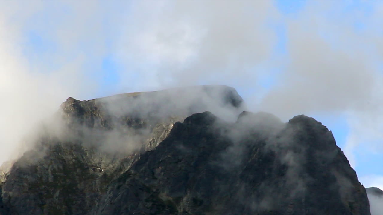 la niebla de la nube matutina se disipa alrededor del pico de la montaña rocosa al amanecer
