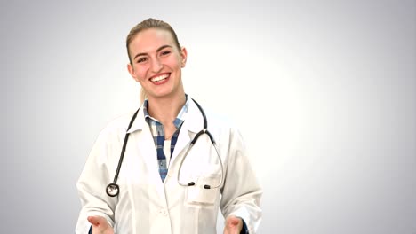 sonriente mujer hermosa en bata de laboratorio hablando con la cámara en fondo blanco