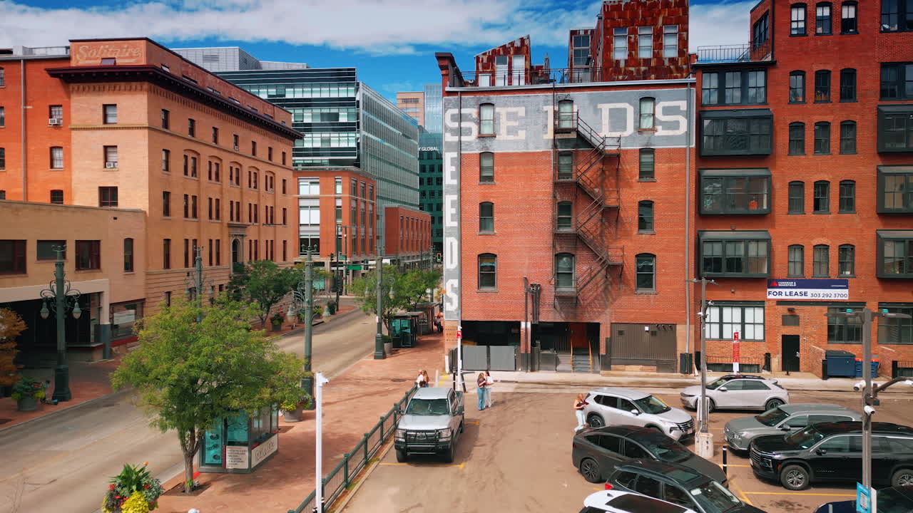 Denver, USA, 28 July 2025: Footage above the parking lot with cars parked. Approaching red-brick multi-storied buildings in Denver, Colorado, USA