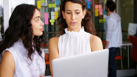 mujeres ejecutivas discutiendo sobre una computadora portátil