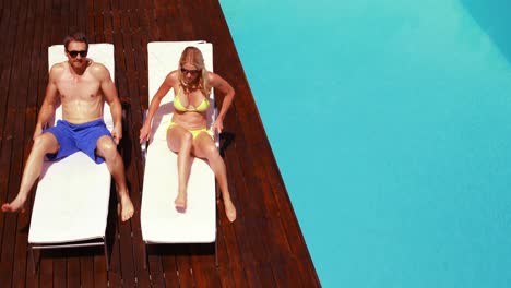 Happy-couple-going-lying-on-deck-chairs