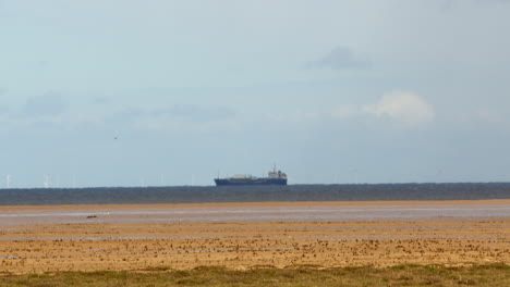 Plano-Amplio-De-La-Playa-Con-Un-Petrolero-Al-Fondo-Con-Neblina-De-Calor-En-Las-Marismas-De-Saltfleet,-Louth,-Lincolnshire