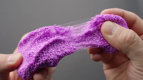 pink floam slime is stretched in a close-up, creating a soft asmr sensory experience.