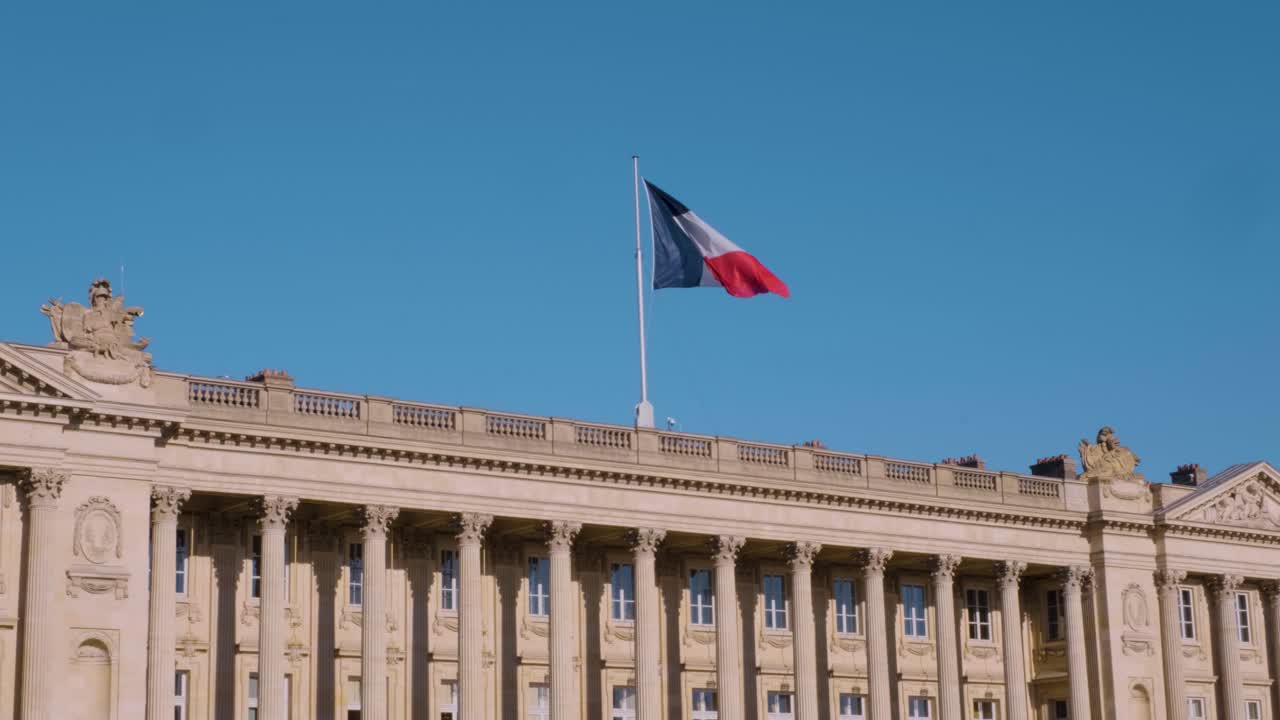 Slow-motion moment of the tricolor flag flying high above the Hôtel de la Marine, bathed in clear daylight