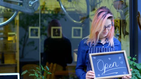 female owner holding chalkboard with open concept 4k