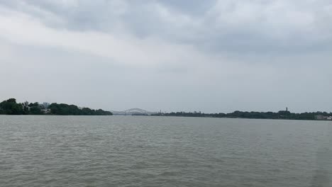 shot of jubilee bridge in distance over the hooghly river between naihati and bandel in west bengal, india on a cloudy day