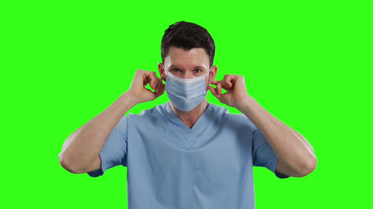 녹색 화면 배경에 얼굴 마스크를 쓰고 있는 백인 남성 의사