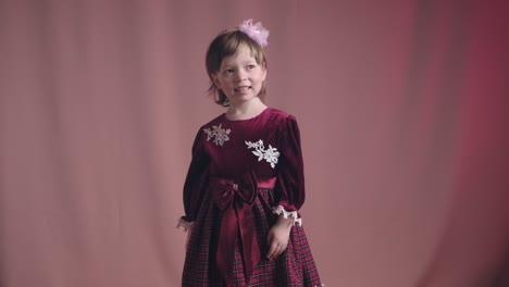 cute little girl in an vintage burgundy dress is spinning in dance and rejoicing