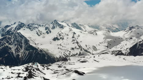 Air-flight-through-mountain-clouds-over-beautiful-snow-capped-peaks-of-mountains-and-glaciers.