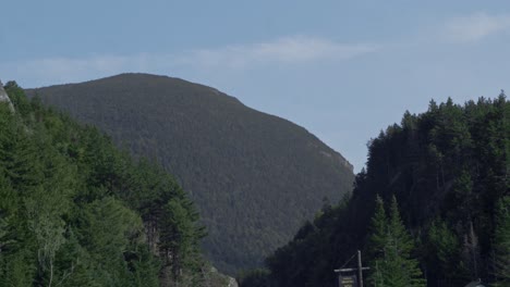 A-road-cuts-through-granite-mountains-as-the-green-mountains-loom-in-the-distance