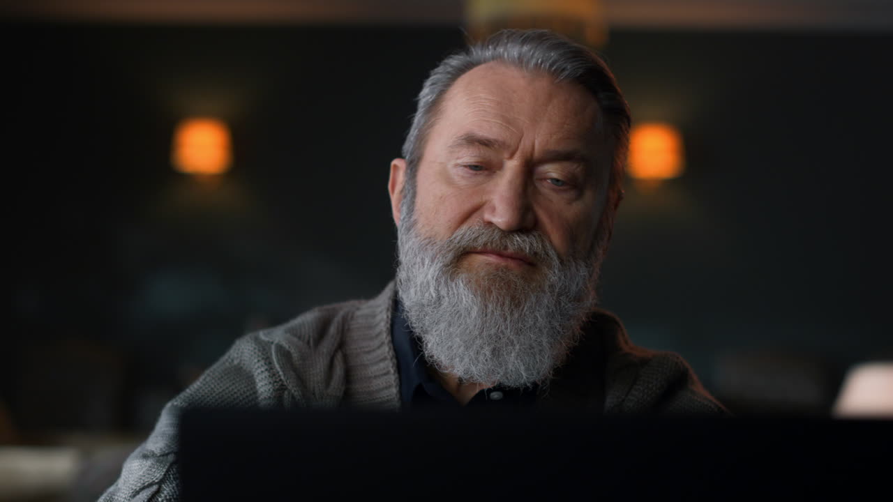 Senior man looking at computer screen home cabinet