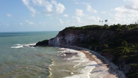 Toma-Aérea-Con-Drones-De-La-Hermosa-Costa-Tropical-De-Paraiba,-Brasil-Cerca-De-Joao-Pessoa-En-El-Punto-De-La-Playa-De-Gramame-Con-Coloridos-Acantilados-De-Arcilla,-Palmeras-Y-Pequeñas-Olas-En-Un-Cálido-Día-De-Verano