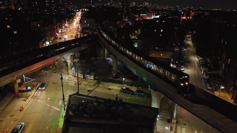 aerial view of a cta train on a bridge, above the illuminated streets of chicago