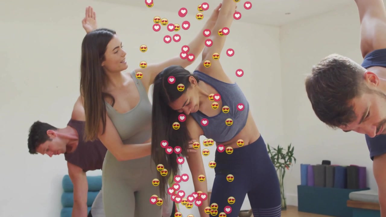 Instruktør veileder student i sidebøy i yogastudio, noe som får hjerteikoner til å sveve opp.