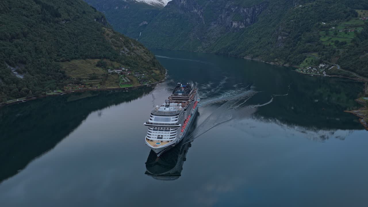 Stort krydstogtskib sejler gennem en dramatisk fjord i Norge, luftfoto