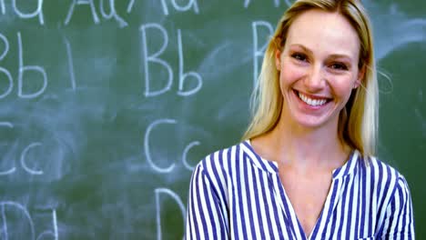 Portrait-of-happy-teacher-standing-with-arms-crossed-in-classroom