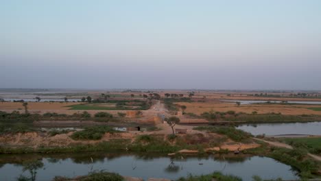 sutlej river intersecting farmlands and a rural road at dusk. punjab, pakistan