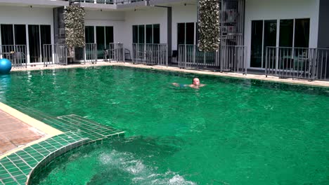 man swims in the pool in hotel