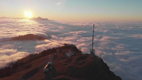 sunset drone view to mountain top surrounded by a sea of clouds