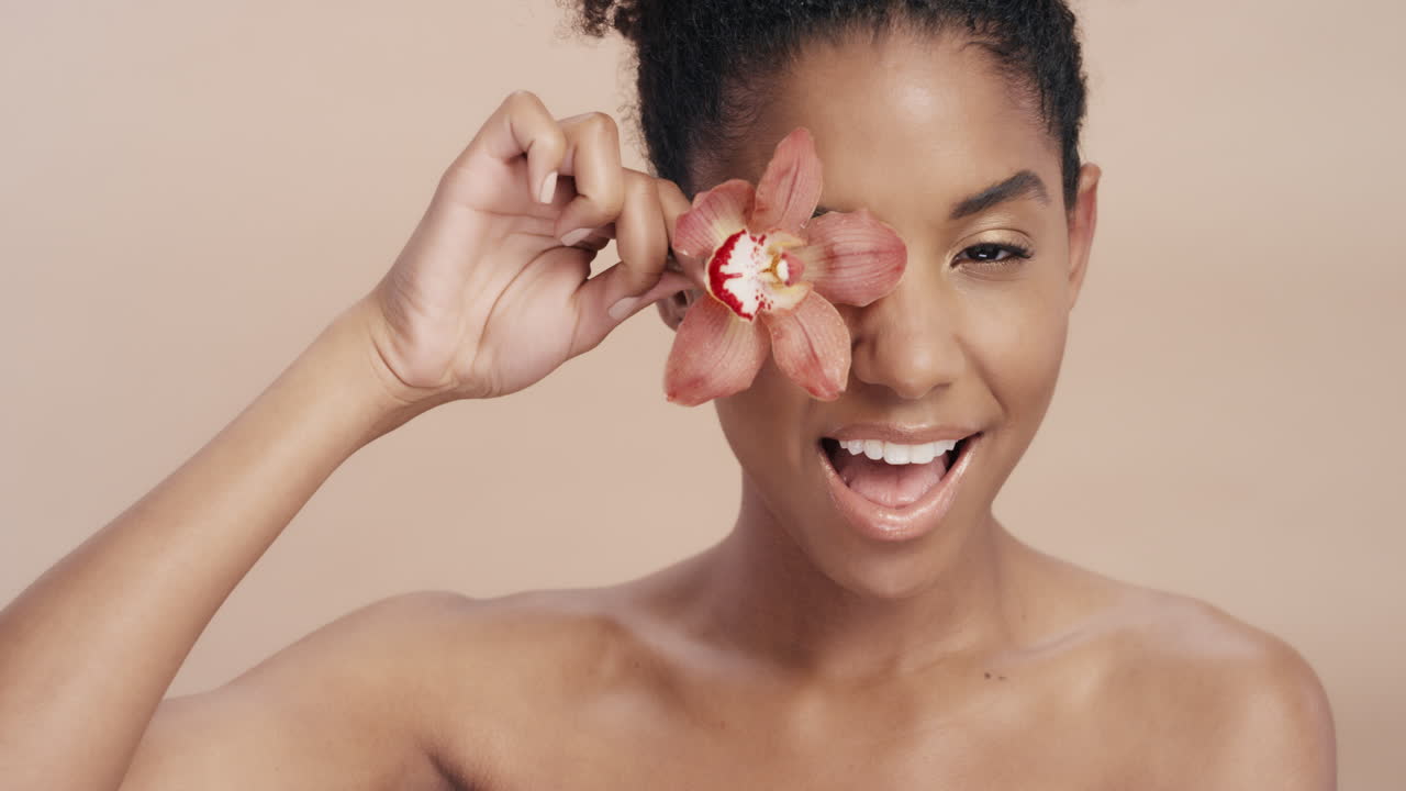 beauty portrait beautiful african american woman playfully posing with orchid flower touching healthy skin complexion enjoying gentle fragrance of natural essence skincare concept