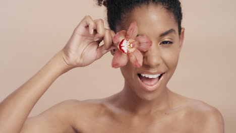 beauty portrait beautiful african american woman playfully posing with orchid flower touching healthy skin complexion enjoying gentle fragrance of natural essence skincare concept