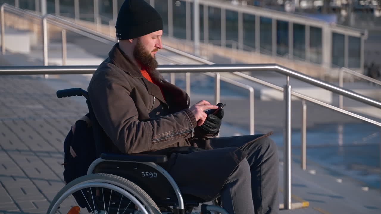 hombre en silla de ruedas usando un teléfono inteligente