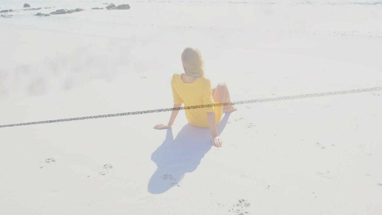 白い砂浜に座り、水面を見つめる女性。そよ風が髪をなびかせ、暗い線が印象的。トラベルマーケティング。