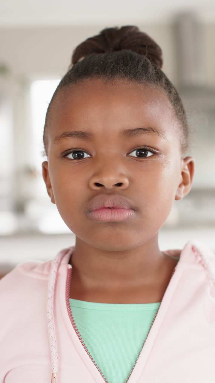 Vertical video of portrait of happy african american girl smiling to camera, in slow motion