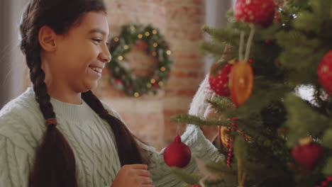 madre y hija afroamericanas decorando el árbol de navidad en casa