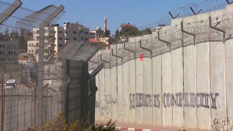 graffiti and barbed wire line the new west bank barrier between israel and the palestinian territories