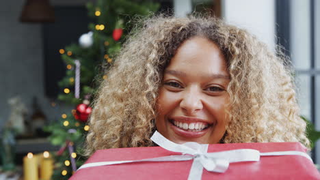mujer llevando una pila de regalos de navidad caminando hacia la cámara
