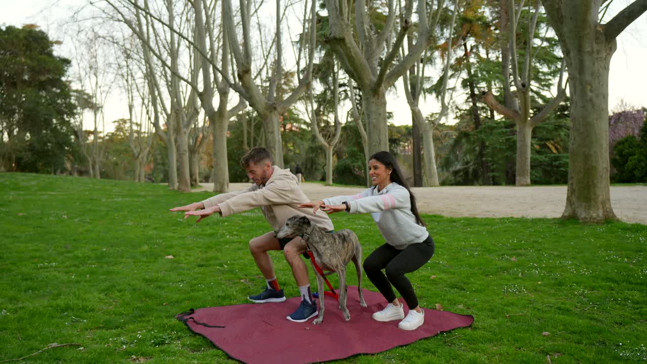 Pareja feliz y perro haciendo sentadillas al aire libre en un parque.
