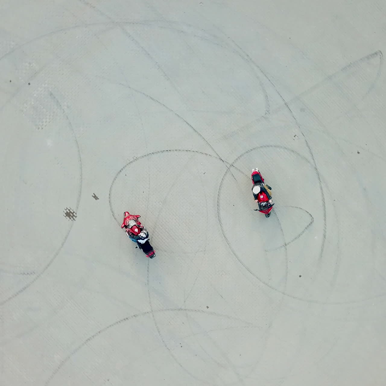 Top view of two professional motobikers racing highspeed on a road in a circle way. Bikers on their motorcycles training riding outdoors. Aerial view.