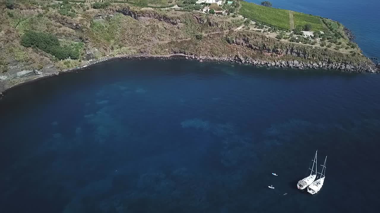 Drone shot of the alone boat on anchorage under island Volcano, Italy, Sicily.
