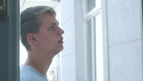 a young man smoking outside of a window