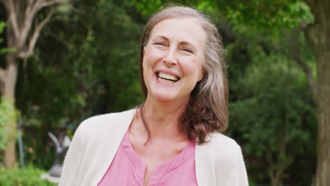 animation of caucasian senior woman smiling at camera in garden