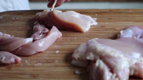 carne de pechuga de pollo cortada en tiras en una tabla de cortar de madera