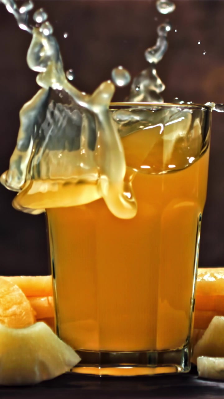 Ananas al rallentatore che si tuffa in un bicchiere di succo fresco