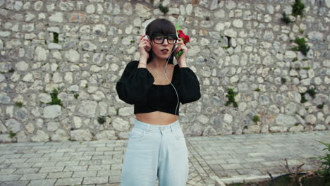 woman with red flowers putting on headphones to listen to music outdoor