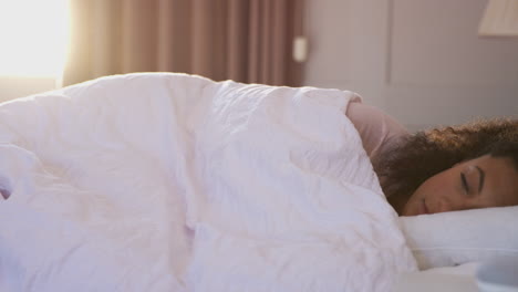 woman waking up in bed with voice assistant on bedside table next to her