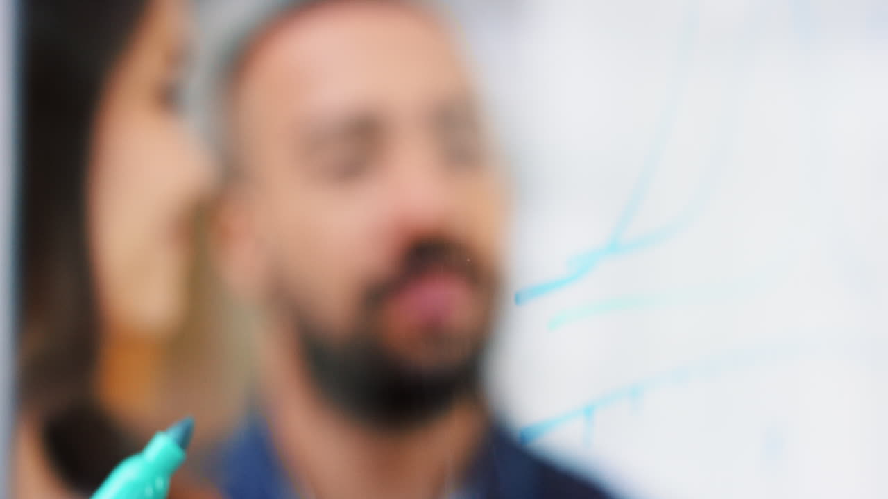 ingeniera dibujando un gráfico en vidrio que muestra una fórmula matemática en una universidad creativa haciendo una lluvia de ideas que muestra a estudiantes trabajando juntos compartiendo datos en un laboratorio de vidrio moderno