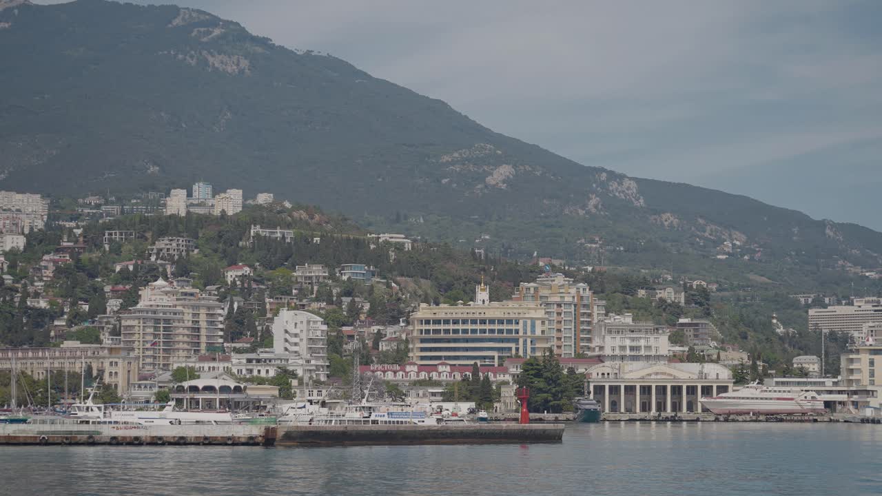 Paesaggio urbano costiero con porto e montagne