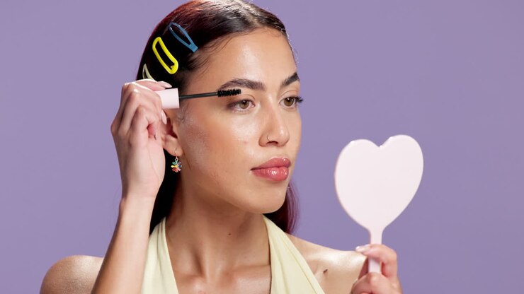 Woman applying makeup with a heart-shaped mirror