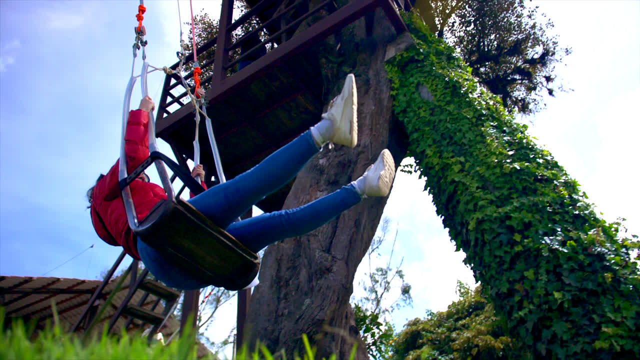 mujer caucásica feliz montando un columpio