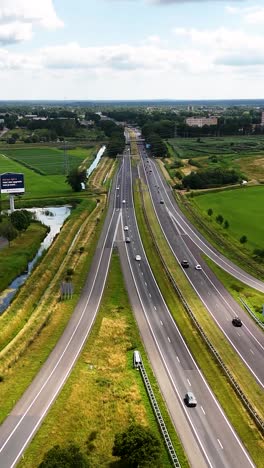 Aerial view of cars driving on a multi-lane highway surrounded by green fields