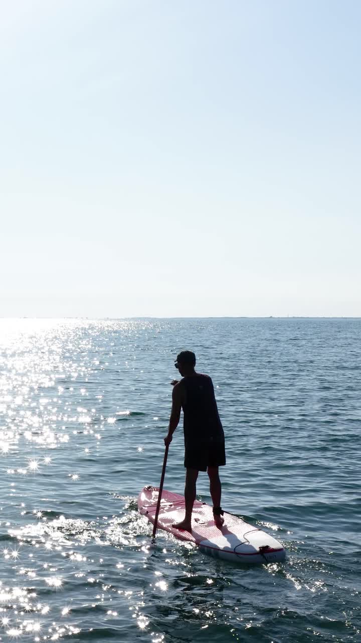 Sportsman paddling on sup board in calm sea. Vertical