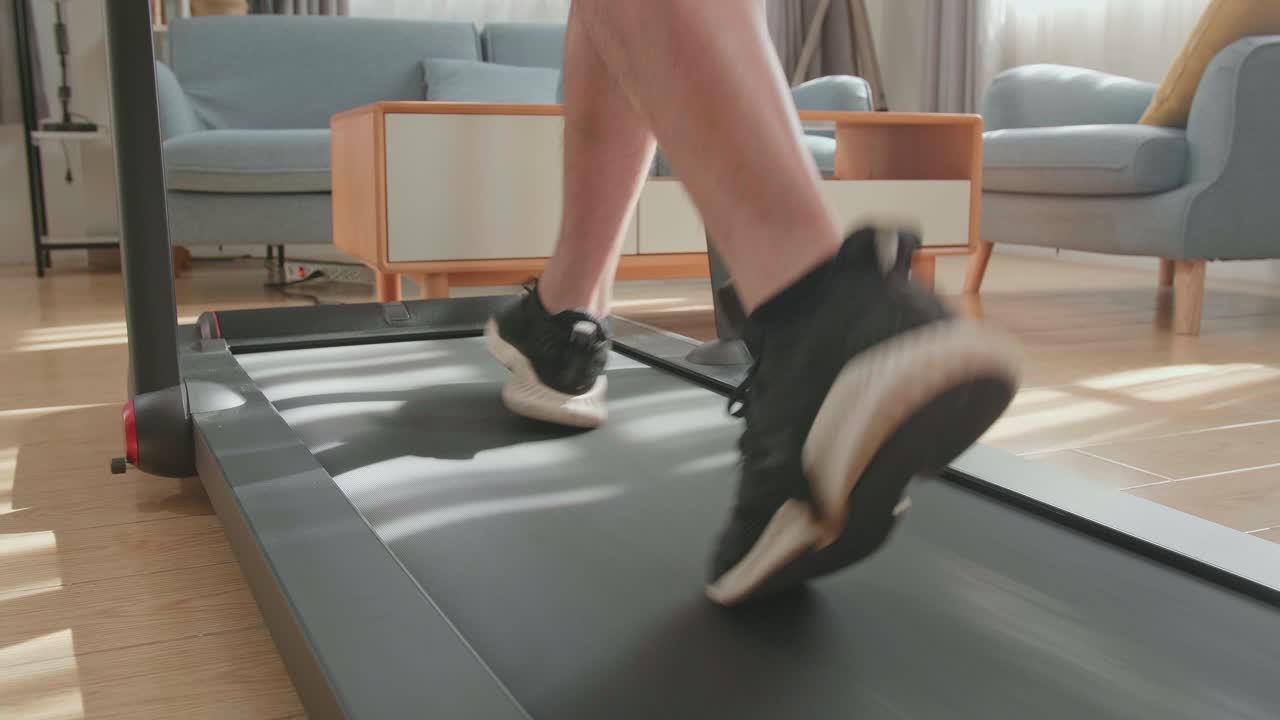 Back View Of Legs Of Asian Man Running On A Treadmill At Home