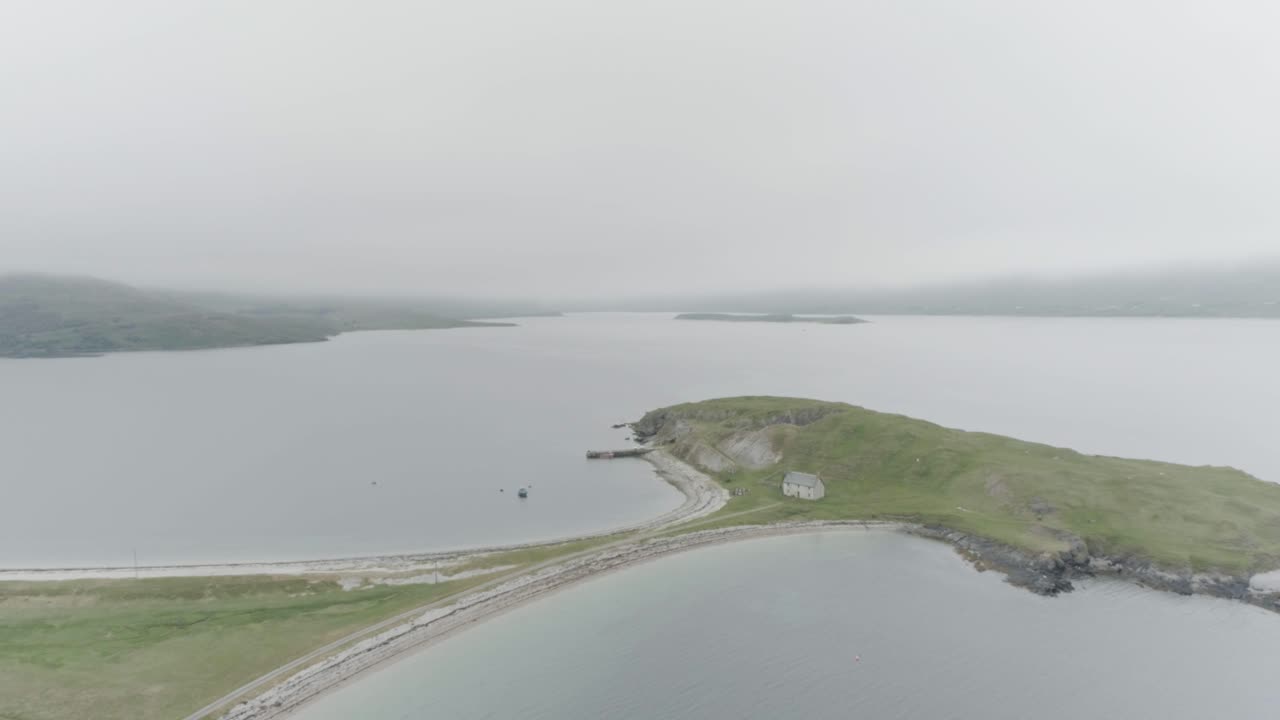 Slow wide drone shot of a small island connected to the mainland with a single house on it outside Durness on the North Coast of Scotland